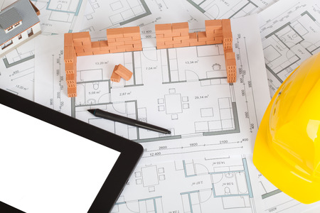 Model house construction with brick on blueprint, helmet and tabletの写真素材