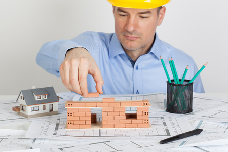 Architect building model house construction with brick on blueprint.の写真素材