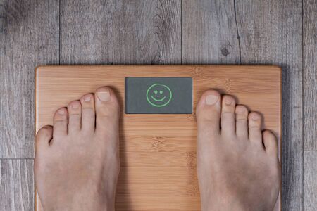 Good weight - display shows smiley. Legs of man standing on weight scale.の写真素材