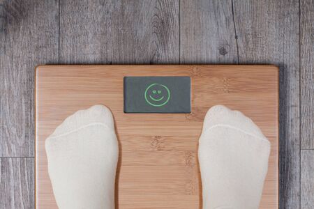 Good weight - display shows smiley. Legs of woman standing on weight scale.の写真素材