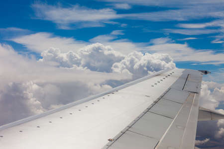 Plane wing, ground, clouds and skyの写真素材