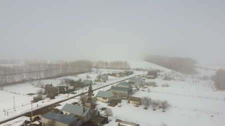village and fields in winter in fog aerialの写真素材