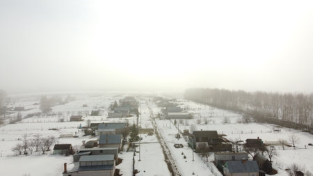 village and fields in winter in fog aerialの写真素材