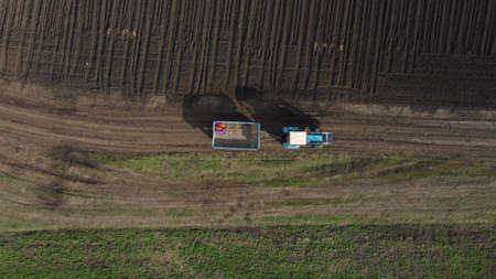 Aerial view of the tractor in the field, agricultural field work, sowing work in the field at sunsetの写真素材