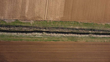 Background of brown earth at high altitude aerial view. Aerial drone view of freshly plowed field ready for seeding and planting in spring.の写真素材