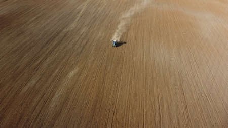 Aerial view of the tractor in the field, agricultural field work, sowing work in the field at sunsetの写真素材