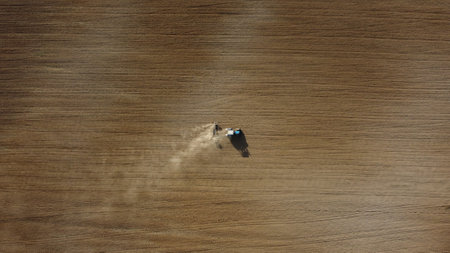 Aerial view of the tractor in the field, agricultural field work, sowing work in the field at sunsetの写真素材