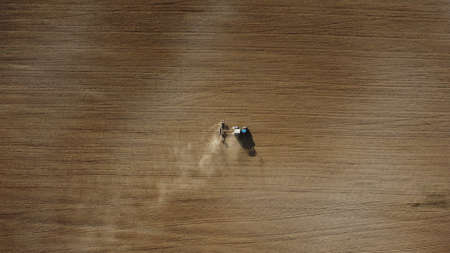 Aerial view of the tractor in the field, agricultural field work, sowing work in the field at sunsetの写真素材
