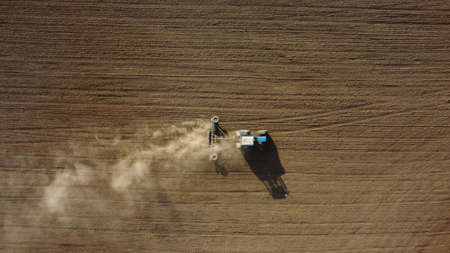 Aerial view of the tractor in the field, agricultural field work, sowing work in the field at sunsetの写真素材