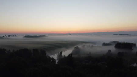 Aerial view of village in fig with golden sunbeams at sunrise in summerの写真素材