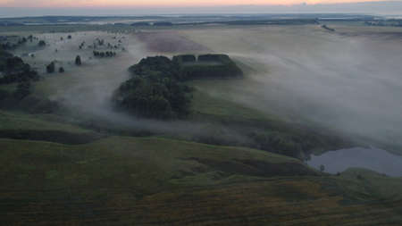 Aerial view of village in fig with golden sunbeams at sunrise in summerの写真素材