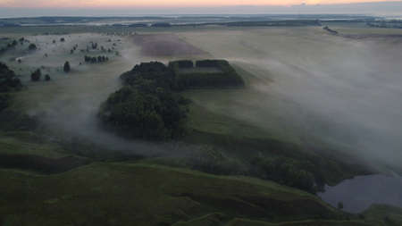 Aerial view of village in fig with golden sunbeams at sunrise in summerの写真素材