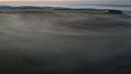 Aerial view of village in fig with golden sunbeams at sunrise in summerの写真素材