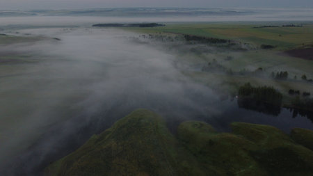 Aerial view of village in fig with golden sunbeams at sunrise in summerの写真素材