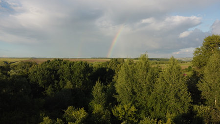 The sky with a rainbow over a meadow rural landscape. View from the heightの写真素材