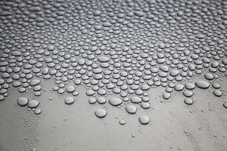 On gray background, water droplets covering upper third of the frame.の写真素材