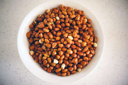 Roasted Asian peanuts or groundnuts (Arachis hypogaea) in a white bowlの写真素材