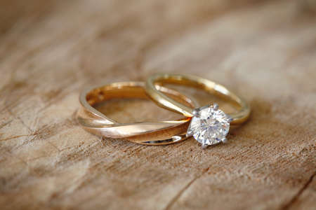 Solitaire engagement diamond ring with wedding band on wooden organic background.の写真素材