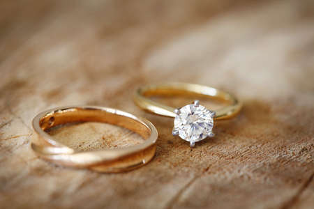 Solitaire engagement diamond ring with wedding band on wooden organic background.の写真素材