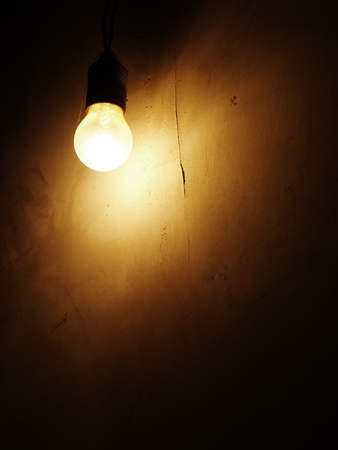 Dusty Incandescent light bulb on a dark wall background の写真素材