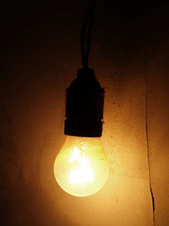 Dusty Incandescent light bulb on a dark wall backgroundの写真素材
