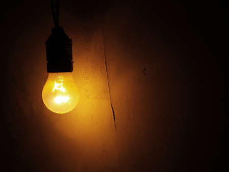 Dusty Incandescent light bulb on a dark wall backgroundの写真素材