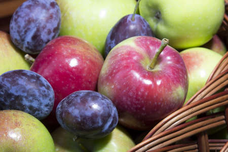 plums and apples in a wicker basketの写真素材