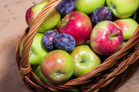 plums and apples in a wicker basketの写真素材