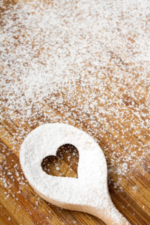 Heart hole spoon on the wooden pastry board - baking backgroundの写真素材