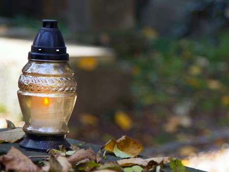 Votive candles at the grave with autumn leaves.の写真素材