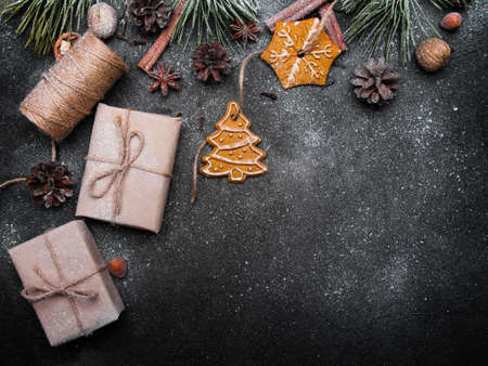 Christmas background with decorations. Christmas presents, gingerbreads, pine twigs and cones covered with snow on dark backgroundの写真素材
