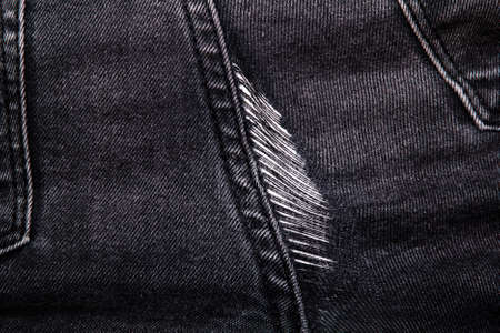 Hole on dark denim jeans. Damaged fabric textureの写真素材