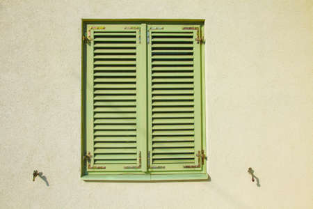 Closed green shutters on a bright yellow wall の写真素材