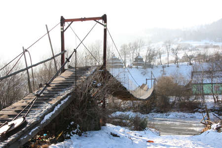 Suspension bridge over the frozen Tisza river in the Carpathians, Ukraineの写真素材