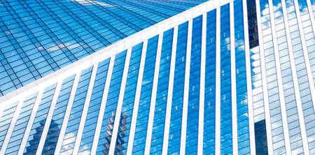 Abstract skyscrapers with reflection in windows blue sky, white clouds and sun glareの写真素材