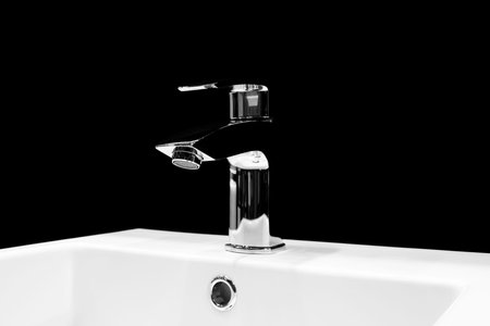 Luxury faucet mixer on a white sink in a beautiful black bathroom