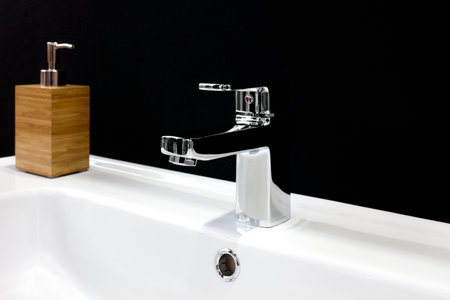 Luxury faucet mixer on a white sink in a beautiful black bathroom