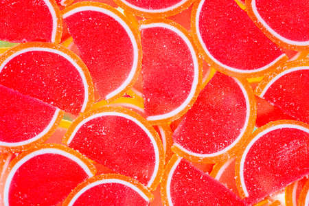 Decorative marmalade candy Background. Pattern of marmalade in shape of citrus fruits wedges. Jelly sweet candies. Food Texture. Beautiful Wide Angle Wallpaper or Web banner. Top view. Flat layの写真素材