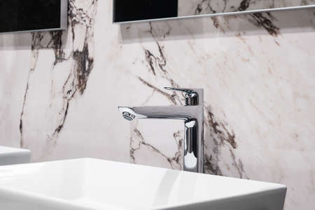Luxury faucet mixer on white rectangular sink in interior of beautiful marble gray bathroom.の写真素材
