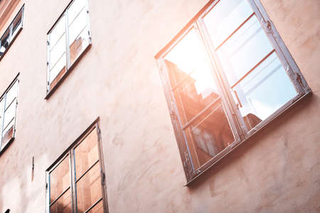 Part of the facade of a red historic building illuminated, reflecting off window panes, in the Old Town Gamla Stan of Stockholm, Sweden. Series - streets of old stockholmの写真素材