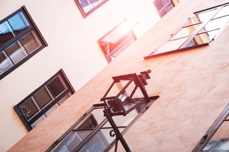 Part of the facade of a red historic building illuminated, reflecting off window panes, in the Old...
