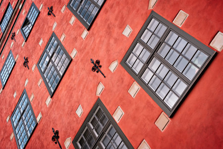 Part of the facade of a red historic building illuminated, reflecting off window panes, in the Old...
