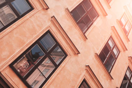 Part of the facade of a red historic building illuminated, reflecting off window panes, in the Old Town Gamla Stan of Stockholm, Sweden. Series - streets of old stockholmの写真素材