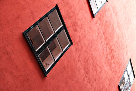 Part of the facade of a red historic building illuminated, reflecting off window panes, in the Old Town Gamla Stan of Stockholm, Sweden. Series - streets of old stockholmの写真素材