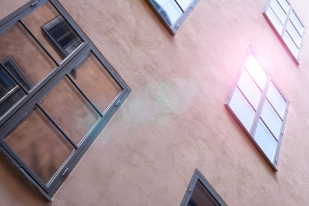 Part of the facade of a brown historic building illuminated, reflecting off window panes, in the Old...