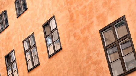 Part of the facade of a brown historic building illuminated, reflecting off window panes, in the Old Town Gamla Stan of Stockholm, Sweden. Series - streets of old stockholmの写真素材