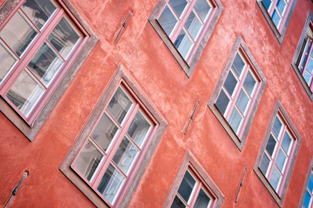 Part of the facade of a red historic building illuminated, reflecting off window panes, in the Old...
