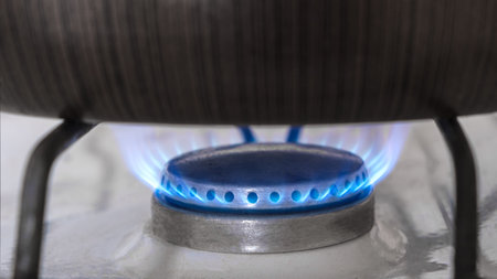 Frying pan on a stove. Natural gas burning on kitchen gas. Panel from steel with a gas ring burner...