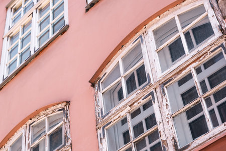 Part of the facade of a red historic building illuminated, reflecting off window panes, in the Old...