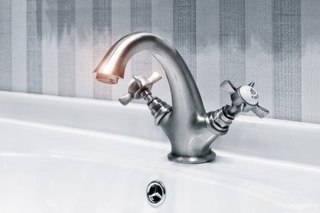 Luxury faucet on a white sink in a beautiful gray bathroom